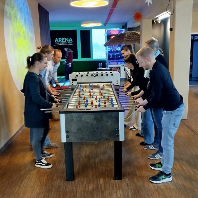 Das Team der HIS während der Weihnachtsfeier Das Team steht an einem Fußballkicker