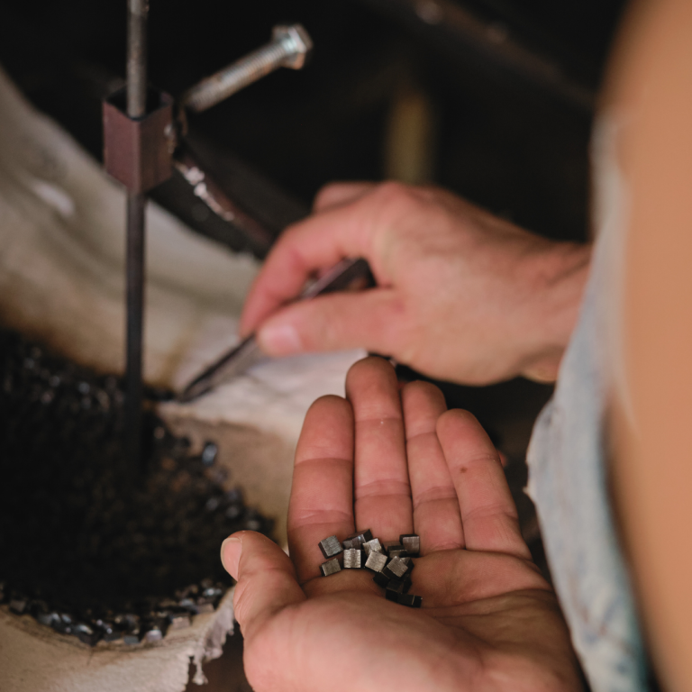 Eine Frau, die mit einer Pinzette industrielle Kleinteile abzählt, um die anschließend zu verpacken.